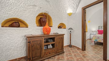 Une pièce au décor rustique, comprenant un meuble en bois doté d’étagères, un lampadaire et des objets de poterie décorative disposés dans des niches.