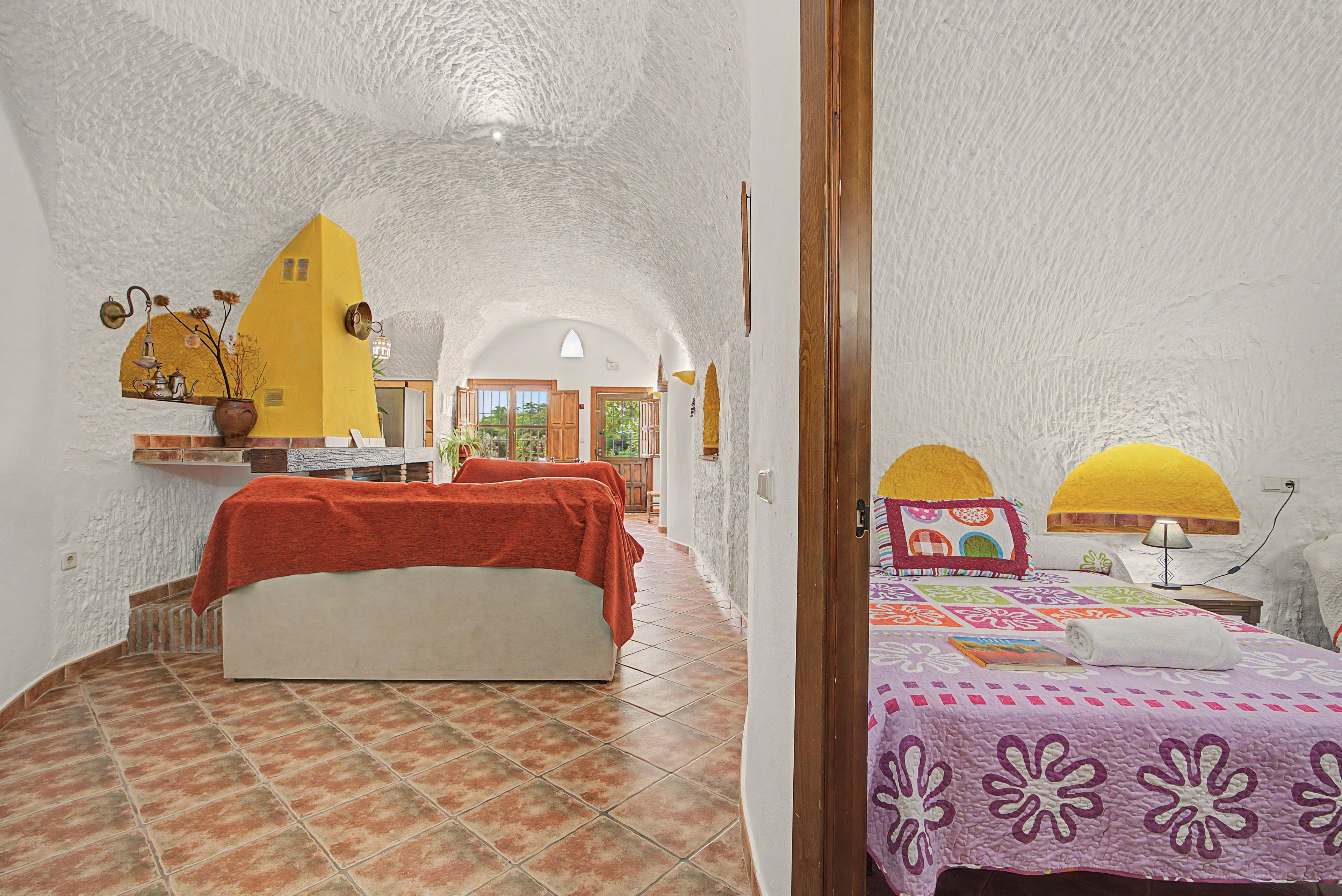 Una habitación con cama, una mesita, una lámpara y un ventanal.