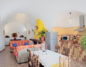 A cozy interior with a dining area, kitchen, and a yellow accent wall. - Country House 'El Olivo' with Shared Pool, Wi-Fi and Air Conditioning (Benalúa)