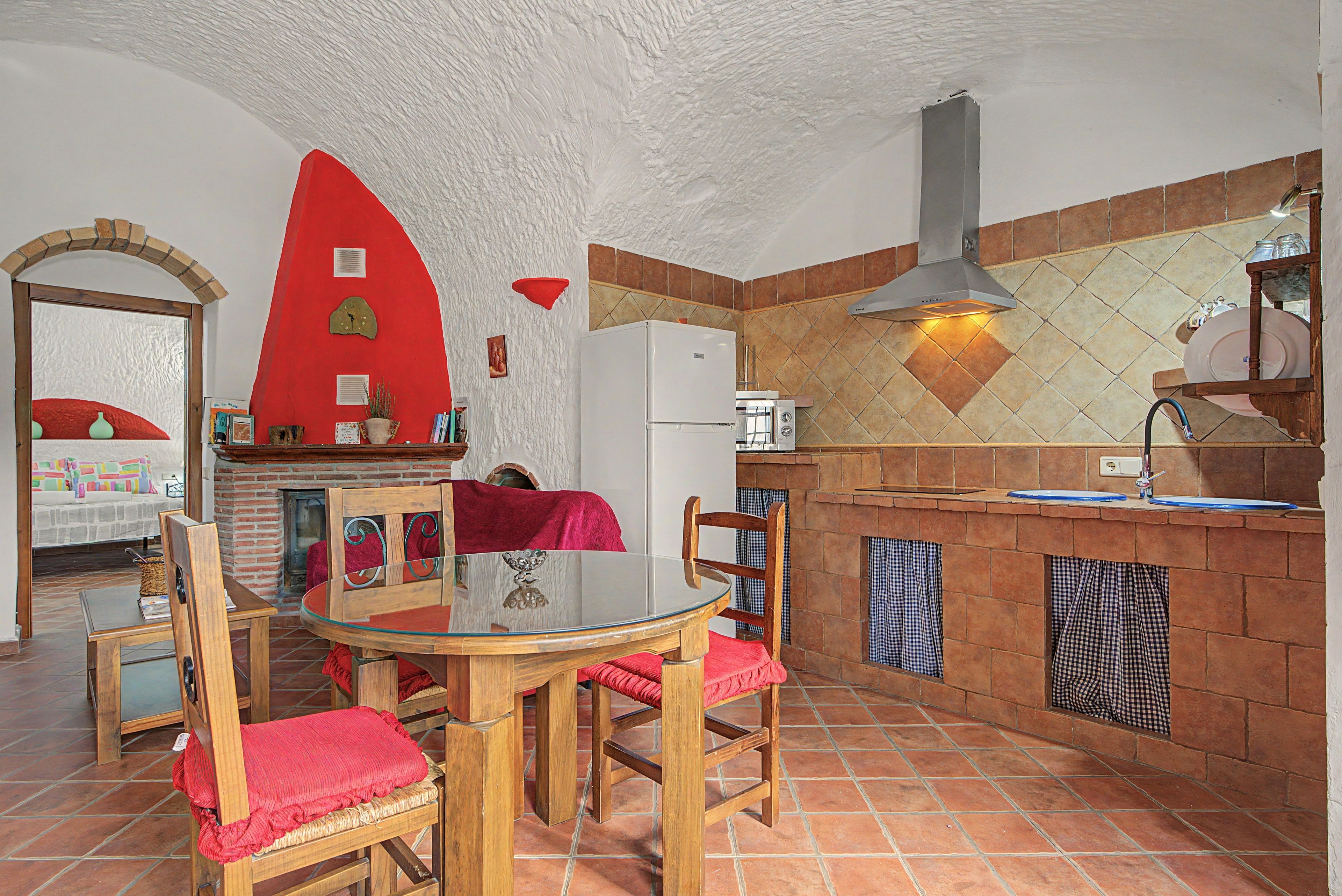 Een keuken met een rode wand, een wit plafond en een betegelde spatwand.