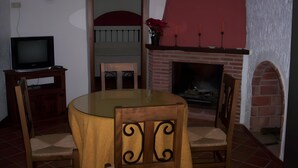 Ein Wohnzimmer mit Fernseher, Kamin und einem Esstisch mit Stühlen.