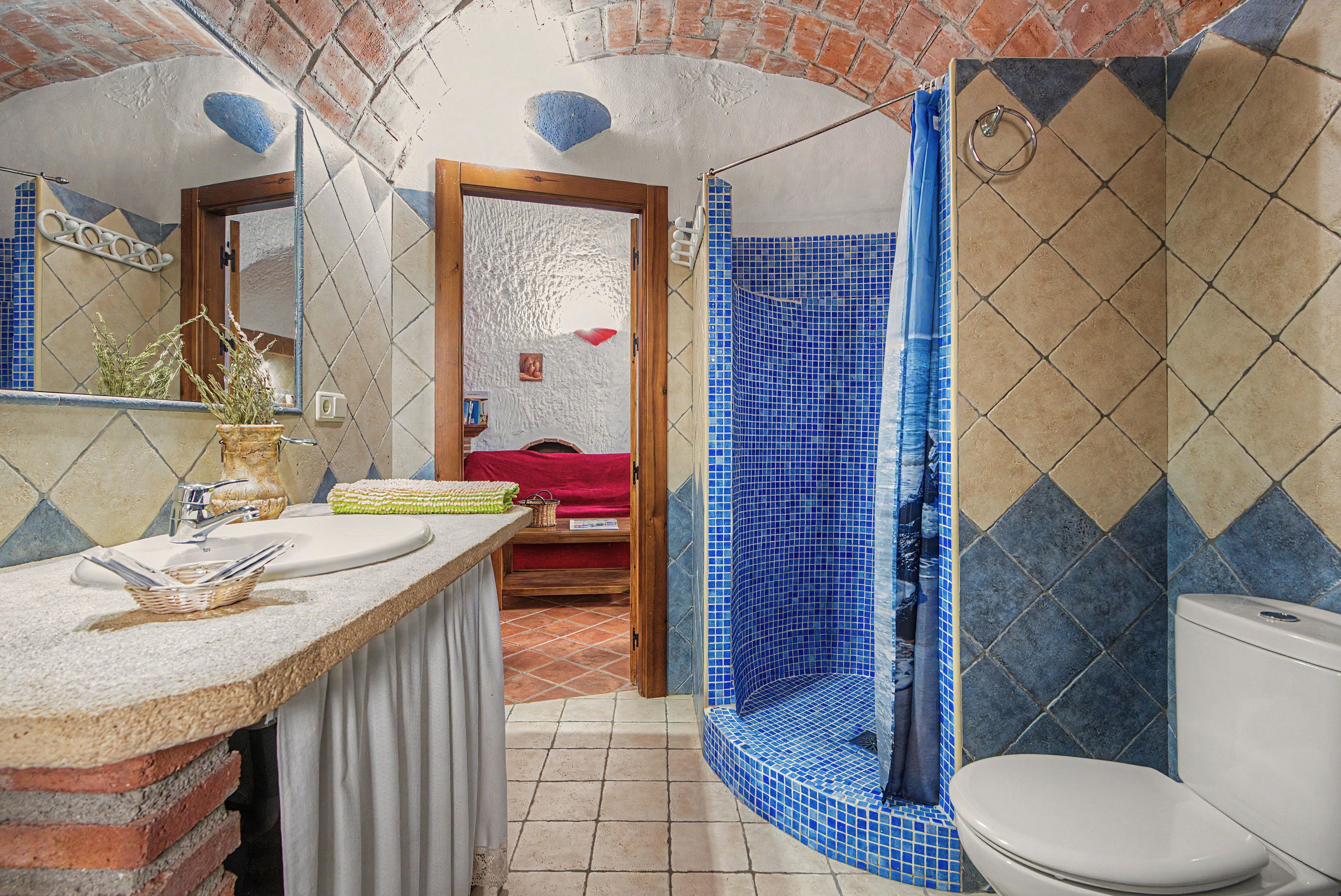 Een badkamer met een betegelde douche, een wastafel en een toilet.