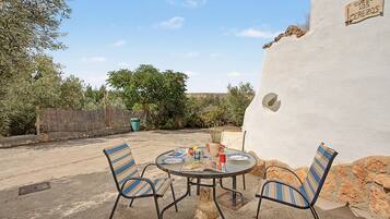 An outdoor patio with a round table, two striped chairs, and a book.