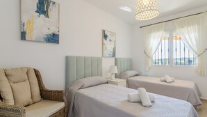 A hotel room with two beds, a wicker sofa, a chandelier, and artwork on the walls. - Villa 'Los Naranjos' with Private Pool, Wi-Fi and Air Conditioning (Mutxamel)