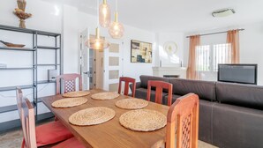 A dining area with a wooden table, woven placemats, and a brown sofa. - Villa 'Los Naranjos' with Private Pool, Wi-Fi and Air Conditioning (Mutxamel)