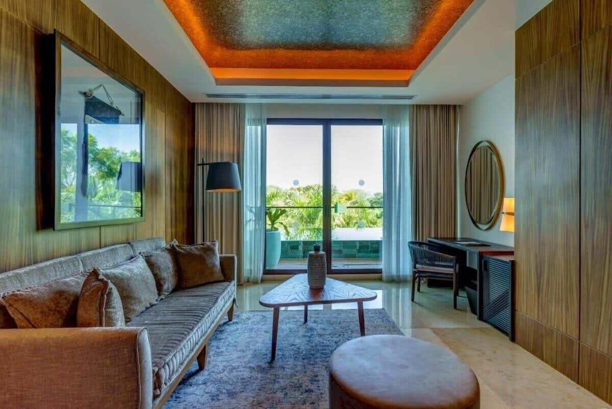 A modern living room with a sofa, coffee table, and a desk with a lamp.