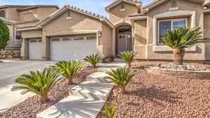A residential house with a garage, a driveway, and a landscaped garden with palm trees. - Copper View-Modern 4BR, Casita, Green Valley (Henderson)