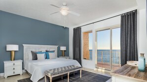 A bedroom with a bed, bedside tables, a bench, a ceiling fan, and a view of the sea through a large window. - Treasure Island 312 | Elite 3BR View (Panama City)
