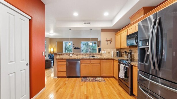 Una cocina moderna con armarios de madera, electrodomésticos de acero inoxidable y piso de madera.