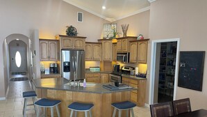 A modern kitchen with a central island, bar stools, stainless steel appliances, and wooden cabinetry. - Three Bedroom Lakefront in home in Quaint Lake Placid Florida (Lake Placid)