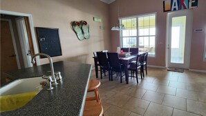 A kitchen with a granite countertop, a sink, and a dining area with chairs and a table. - Three Bedroom Lakefront in home in Quaint Lake Placid Florida (Lake Placid)