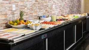 A buffet with various food items and a stone wall background.