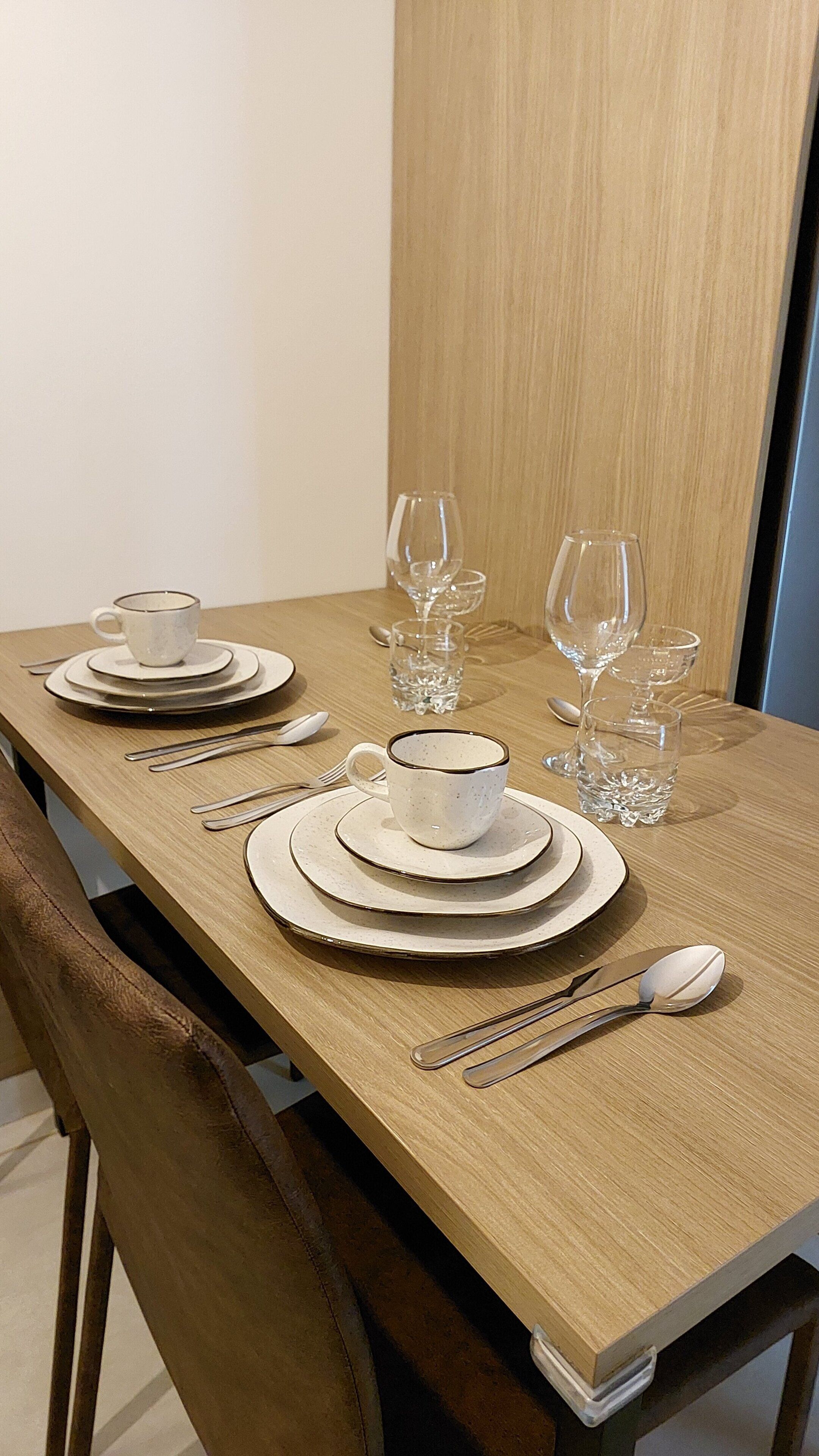 A dining table set with plates, cups, cutlery, and glasses.