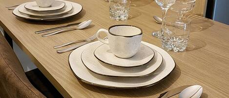 A dining table set with plates, cups, cutlery, and glasses.