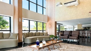 A spacious living area with a large window, a sofa, a coffee table, and a dining area with chairs.