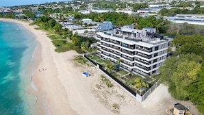 Un hôtel moderne à plusieurs étages, doté de balcons, situé sur une plage avec vue sur l’océan.