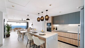 Une cuisine moderne dotée d’un îlot central, de meubles en bois et de luminaires suspendus.