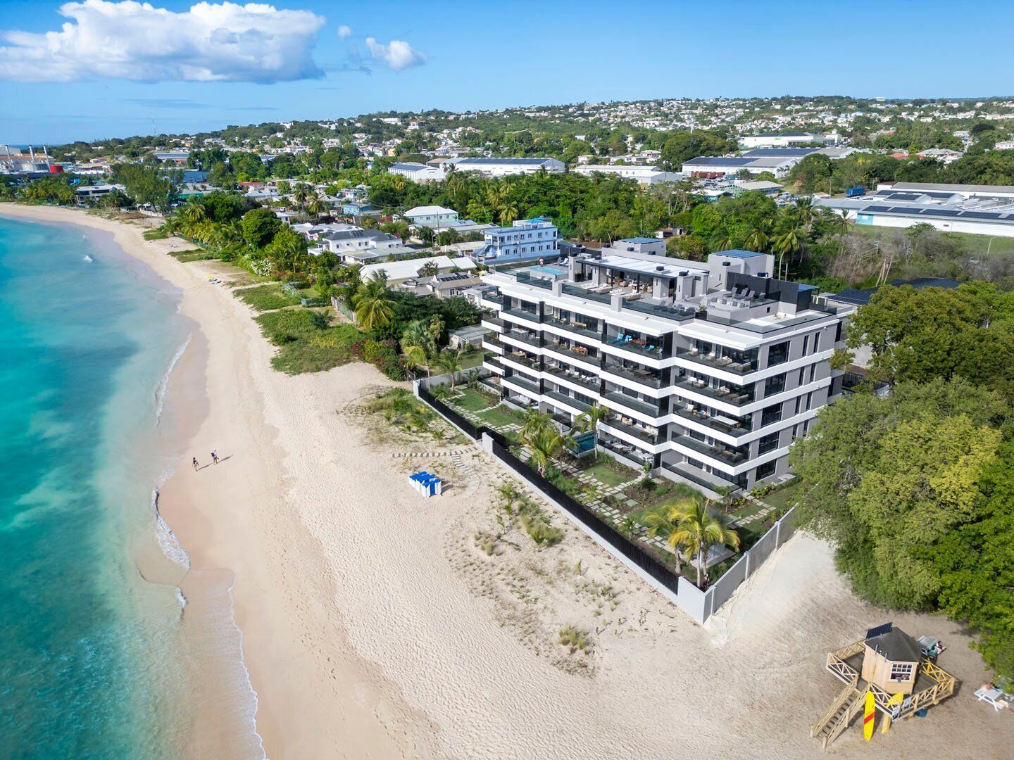 Un hôtel moderne à plusieurs étages, doté de balcons, situé sur une plage avec vue sur l’océan.