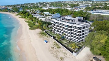 Un hôtel moderne à plusieurs étages, doté de balcons, situé sur une plage avec vue sur l’océan.
