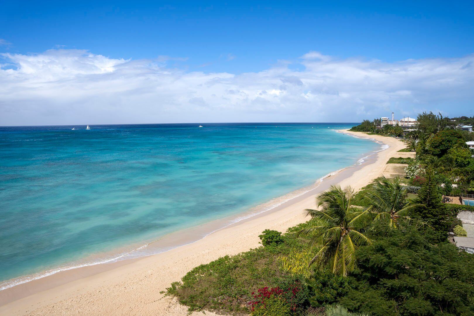 Une plage aux eaux turquoise et limpides, bordée d’un rivage sablonneux et d’une végétation luxuriante.