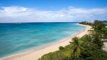 Une plage aux eaux turquoise et limpides, bordée d’un rivage sablonneux et d’une végétation luxuriante.