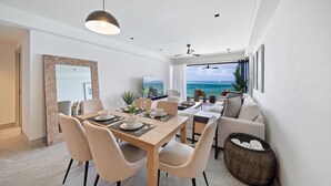 Un espace repas moderne avec vue sur l’océan, un canapé et un téléviseur.