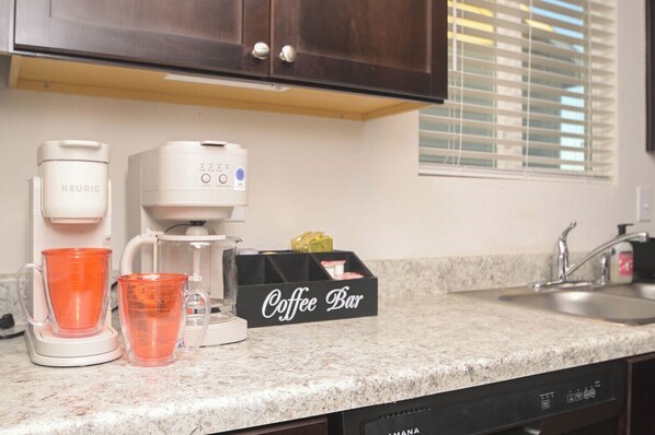 Una cocina con cafetera, letrero de barra de café y lavavajillas.
