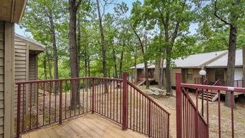 A wooden deck with a red railing leading to a covered area with picnic tables.