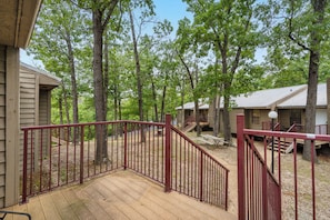 A wooden deck with a red railing leading to a covered area with picnic tables.