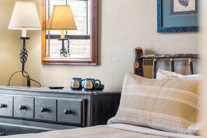 Un dormitorio con cama, cómoda, lámpara y un cuadro en la pared.