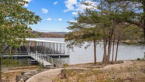 A dock extending into a calm lake with a metal railing and steps leading down to the water.