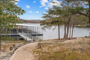 A dock extending into a calm lake with a metal railing and steps leading down to the water.