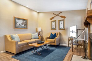 A living room with a sofa, armchair, coffee table, and a fireplace.