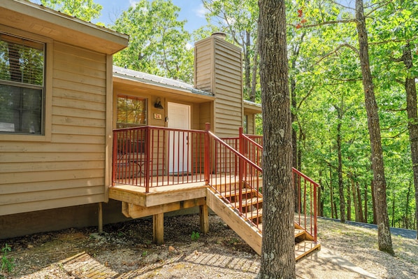 A wooden cabin with a porch and a staircase leading to a deck.