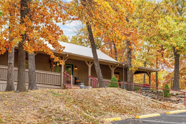 A lodge with a porch, wooden exterior, and a stone wall.