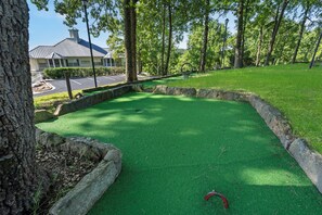 A miniature golf course with a green artificial turf, stone borders, and a red golf ball.