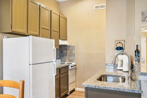 A compact kitchen with a refrigerator, stove, and sink.