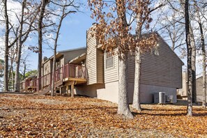 A multi-story building with a balcony, surrounded by trees and fallen leaves.