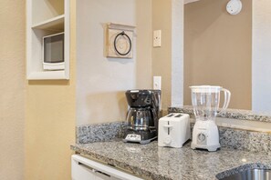 Cozinha com cafeteira, torradeira e liquidificador no balcão.
