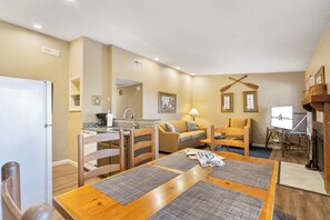Un espacio habitable compacto con kitchenette, una zona de comedor y un área de estar con sofá y sillas.