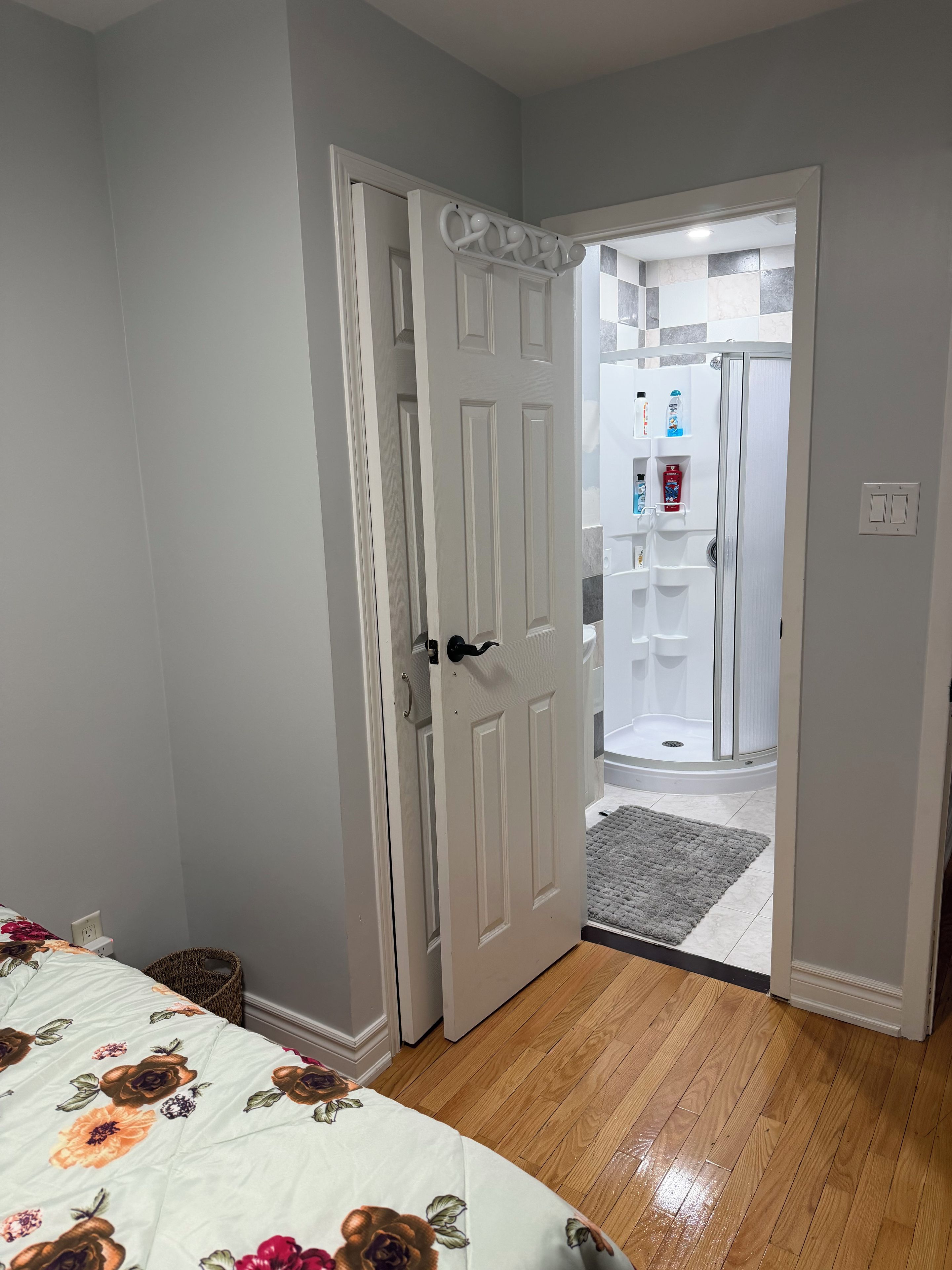 A bedroom with a bed, a door leading to a bathroom, and a wooden floor.