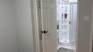 Une chambre à coucher avec un lit, une porte donnant sur une salle de bain et un plancher en bois.