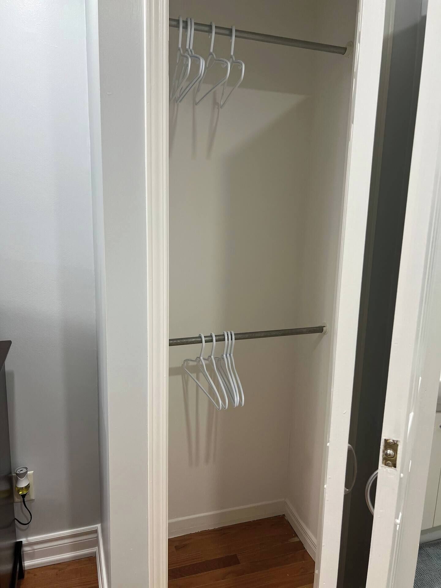 A walk-in closet with two rows of white hangers on metal rods.