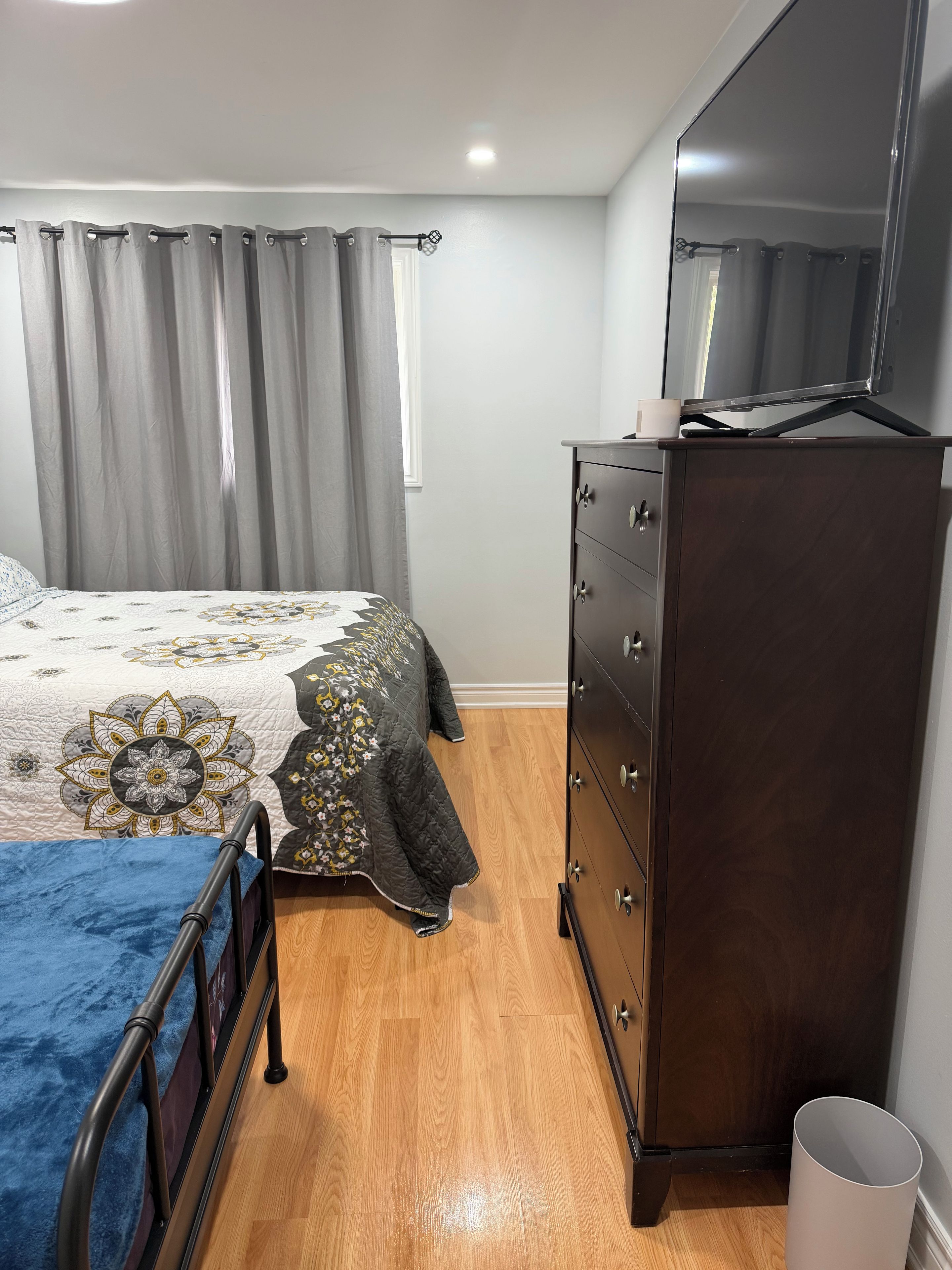 A bedroom with a bed, dresser, and a television.