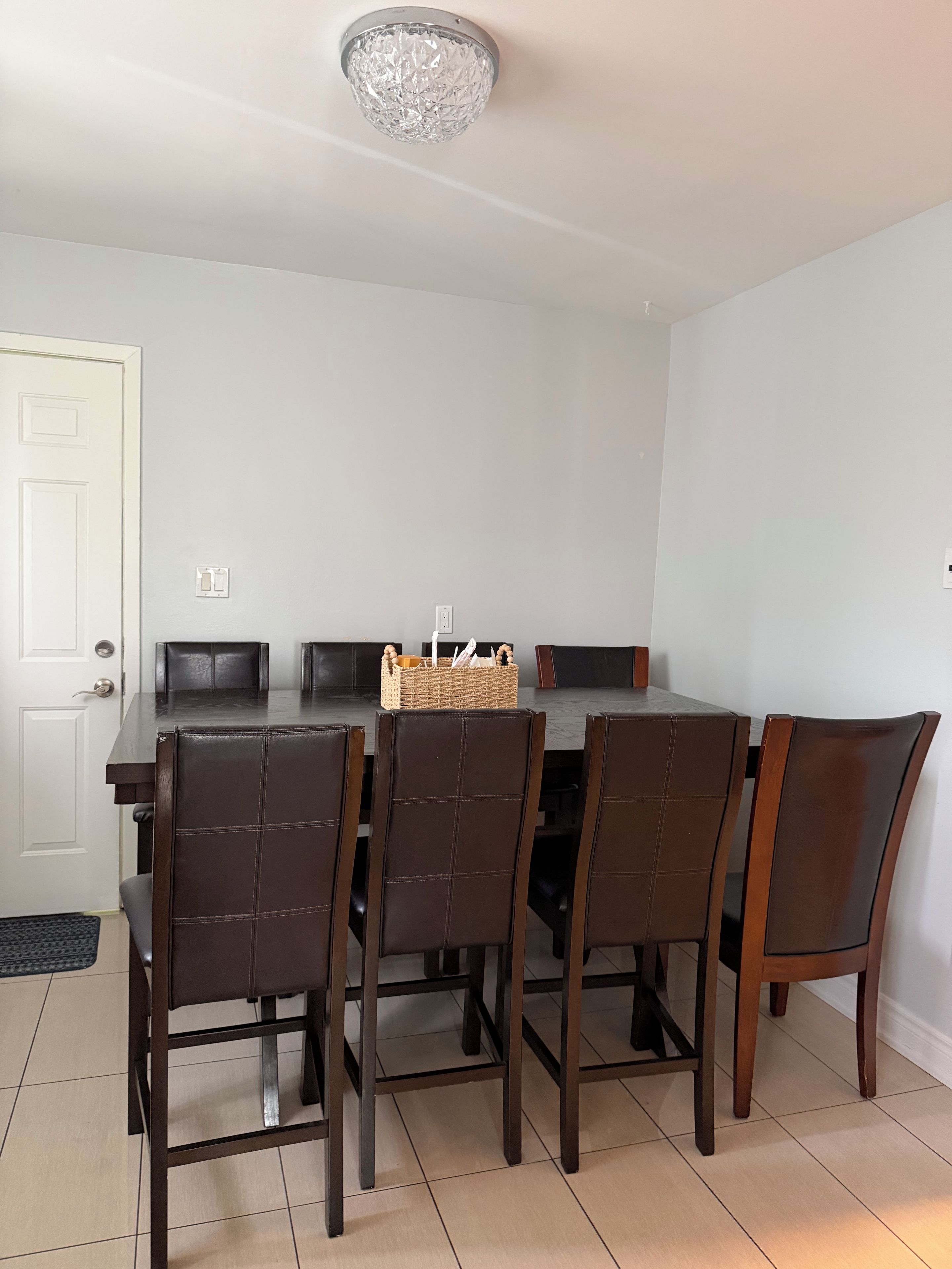 A dining area with a table and chairs, a chandelier, and a door.