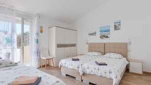 A bedroom with a bed, a chair, a wardrobe, and artwork on the wall.