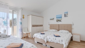 Un dormitorio con cama, una silla, un armario y cuadros en la pared.