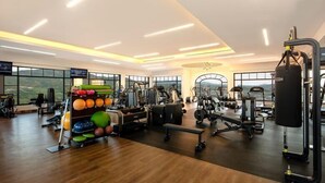Un gimnasio moderno con diverso equipo de ejercicio, ventanas amplias y suelo de madera.