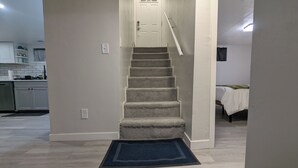 A staircase leading to a bedroom with a bed and a nightstand.