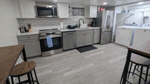 A modern kitchen with stainless steel appliances, white cabinetry, and a wooden dining table.